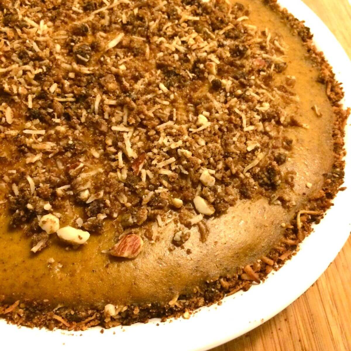 baked dark golden brown maple pumpkin pie with nut crust base and sprinkle topping.