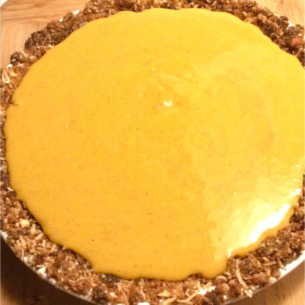 Bright golden brown maple pumpkin pie filling poured into baked nut crust.